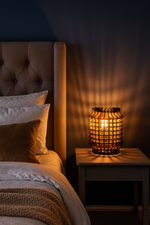 Bedroom scene with a MDF night lamp on a nightstand next to a bed with pillows.
