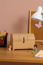 MDF treasure chest on a desk with stationery items and a lamp in the background.