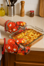 Person wearing tomato-patterned oven mitts holding a dish of lasagna.