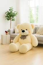 3 feet yellow teddy bear with a gray bow tie in a bright living room.