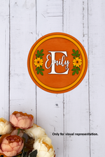Customized round MDF name plate with floral design and name Emily in orange background.