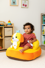Child sitting on a yellow and orange plush sofa seat in a room with books and toys.