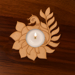 Decorative MDF peacock and lotus design T-light holder with a lit white candle placed on a wooden surface, ideal for Indian festive and pooja decor.