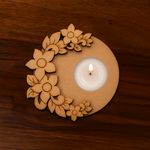 Handcrafted MDF round tealight holder with flower pattern and a lit candle in center on a dark wooden base