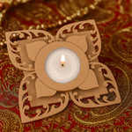 Laser-cut floral MDF tealight candle holder with lit candle, placed on ornate red and gold decorative fabric