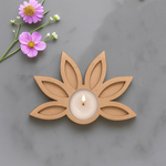 Lotus shape MDF tea light candle holder with lit candle and floral decoration on marble surface