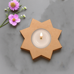 Flower shape MDF tea light candle holder with lit candle and floral decoration on marble surface