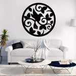 Black circular bird and leaf wall decor featuring intricate designs of a bird surrounded by swirling leaves, mounted on a white wall above a modern living room setup with a sofa and coffee table