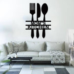 Black MDF wall art featuring the phrase "MOM'S KITCHEN" with a fork, spoon, and knife design, mounted on a white wall above a modern sofa in a stylish living space.