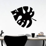 Black palm leaf wall art displayed above a minimalist desk setup.