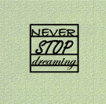Black MDF wall art featuring the motivational phrase "NEVER STOP dreaming" in elegant typography, mounted on a textured light green wall.