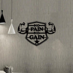 Black MDF wall art featuring the motivational phrase "NO PAIN NO GAIN" inside a shield design with flexed biceps on either side, mounted on a textured gray wall