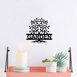 Black garden wall art featuring a tree design with heart-shaped leaves and the word "GARDEN," mounted on a white wall above a shelf with decorative items.