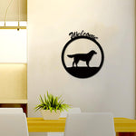 Black MDF wall art featuring a silhouette of a dog within a circular frame and the word "Welcome" on top, mounted on a beige wall above a modern dining table with a plant centerpiece.