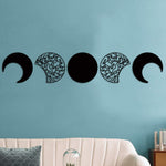 Decorative wall art featuring the phases of the moon with intricate patterns on a teal wall above a modern sofa.