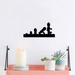 Black evolution-themed wall art depicting the progression of human evolution, mounted on a white wall above a coral shelf with decor items.