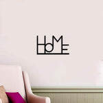 Minimalist black 'Home' wall decor mounted above a cozy living room chair with a purple cushion, adding a modern touch to the soft neutral wall.