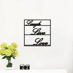 Elegant black Laugh, Live, Love wall art with a sleek frame, mounted on a white wall above a minimalist white table adorned with a vase of green flowers and a vintage camera