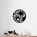 Circular black MDF wall art with an abstract cutout design resembling flowing patterns, mounted on a white wall above a modern wooden shelf with decorative items