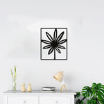 Minimalist black flower wall decor in a rectangular frame, mounted above a white console table with decorative items and plants.