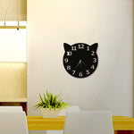 Black wall clock with a cat-ear design and bold white numerals, mounted on a light-colored wall above a dining table with a potted plant centerpiece, in a modern dining area