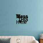 Bless This Home wall art in black with heart design, mounted on a teal wall above a stylish beige sofa in a modern living room