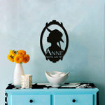 Vintage wall art featuring a black silhouette of a girl in a hat within an ornate oval frame, mounted on a light blue wall above a bright blue console with decorative items.