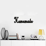 Charming black 'Homemade' wall decor mounted above a sleek black marble console table, styled with books, decorative vases, and a warm-toned table lamp.