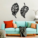 Two intricately designed black MDF feather wall decor pieces mounted on a wall above a modern teal sofa, complementing the cozy living room setup.
