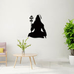 Black God Shiv wall art featuring a meditative silhouette of Lord Shiva with a Trishul, mounted on a white wall in a serene setting with greenery and minimalist decor.