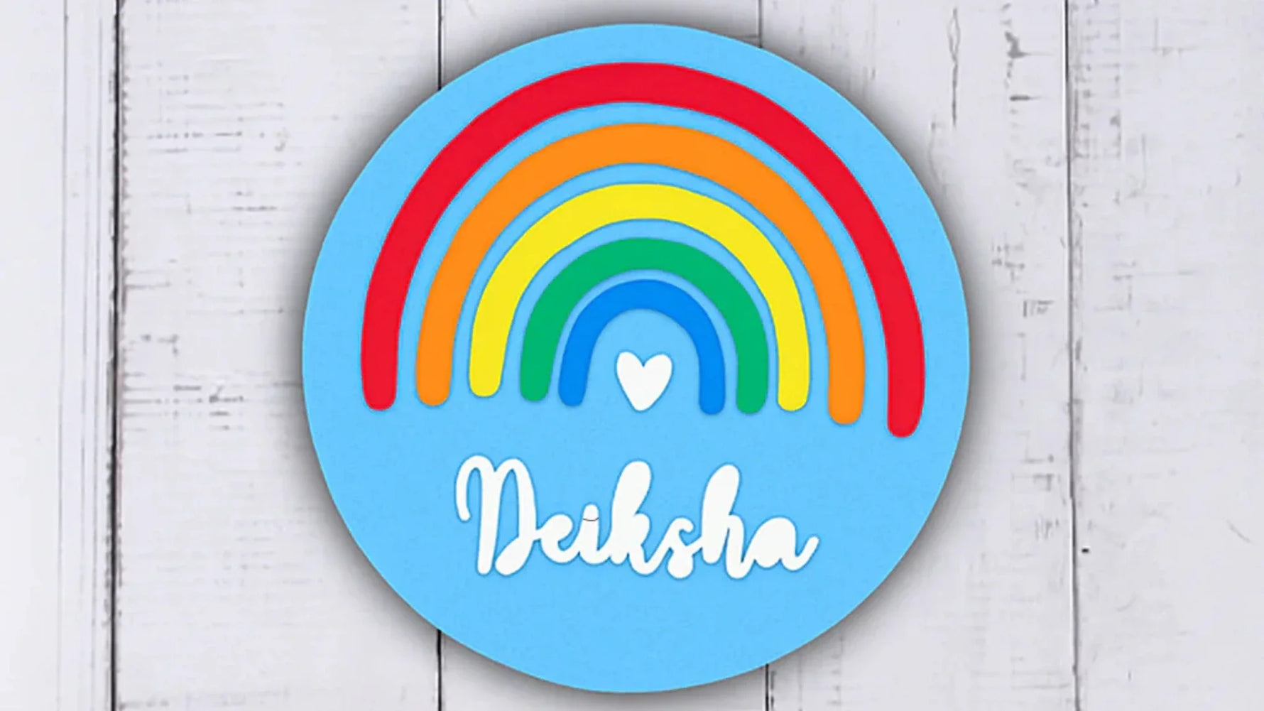 Rainbow MDF name plate with colorful arcs and the name “Deiksha” on a sky-blue circular base.