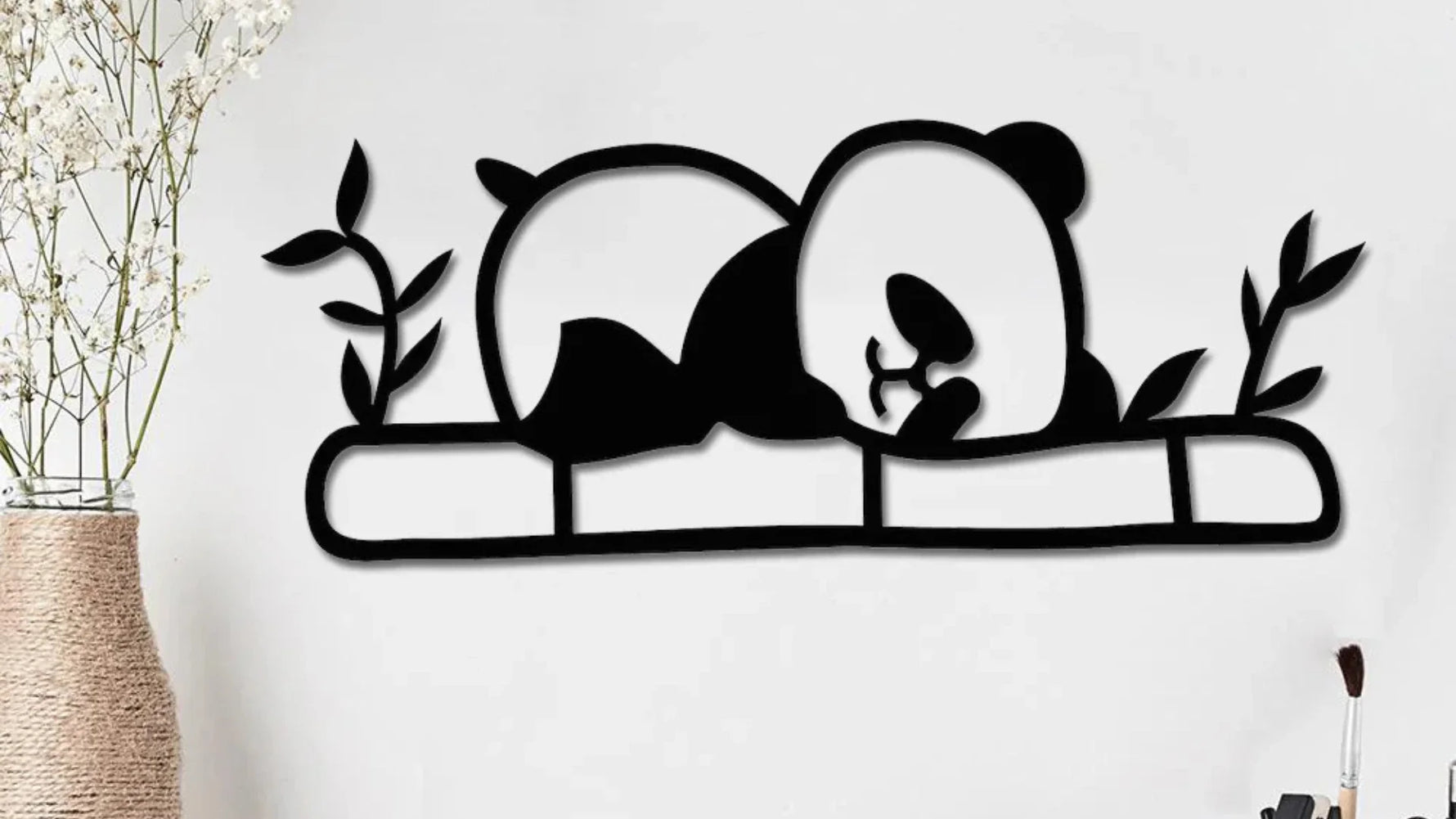 Sleeping panda metal wall art décor on a modern white wall with decorative plants.