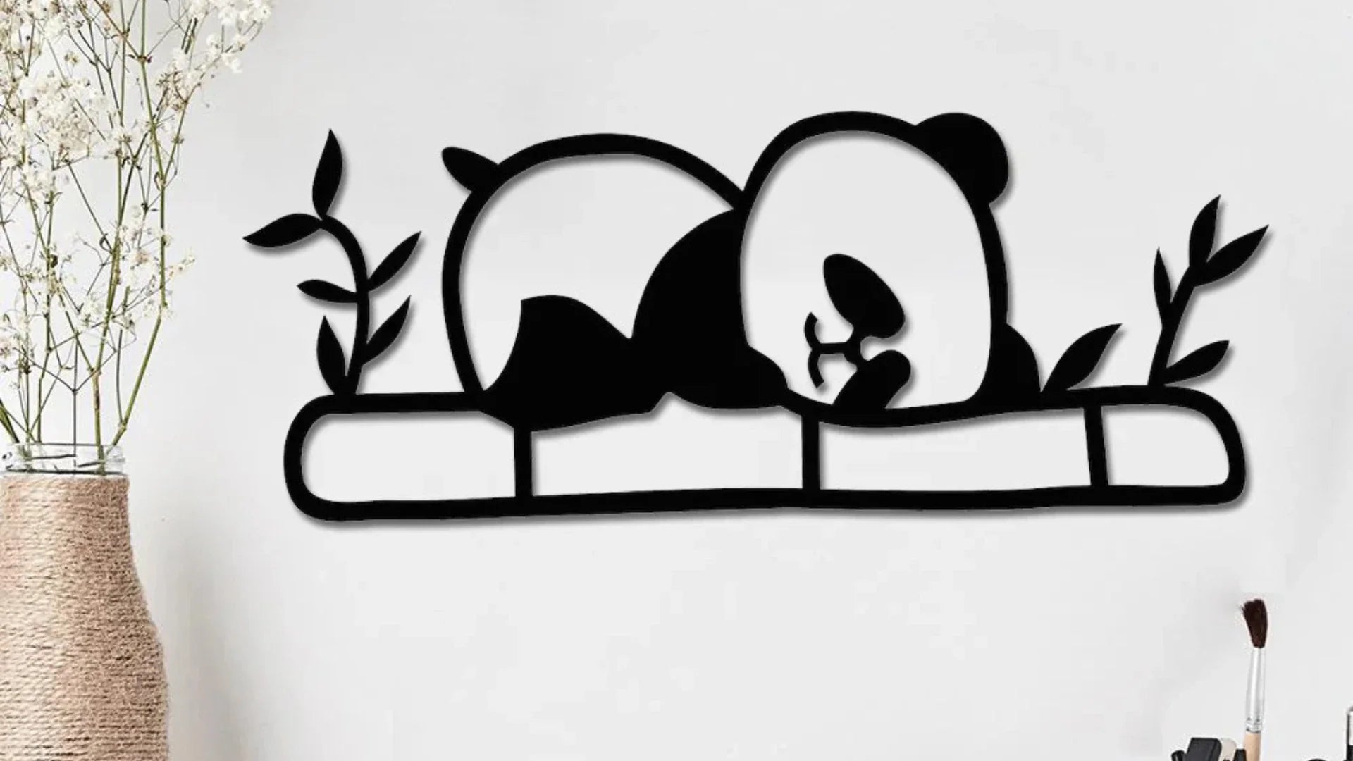 Sleeping panda metal wall art décor on a modern white wall with decorative plants.