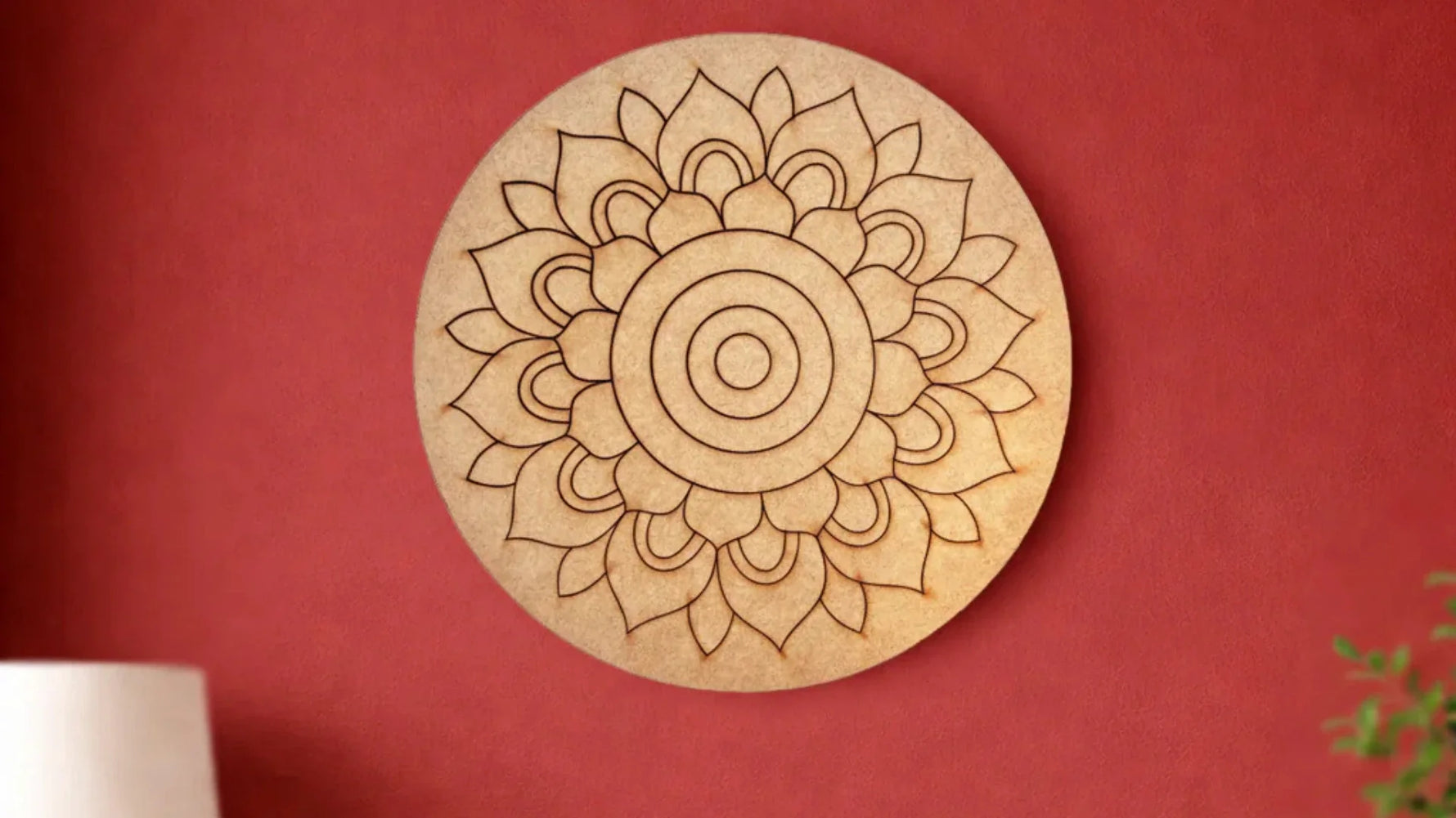 Unfinished round MDF mandala wall décor with floral engraved design mounted on a red wall.