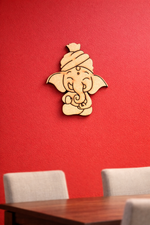  MDF DIY Ganesha wall decor on a red wall with a wooden table and chairs below.