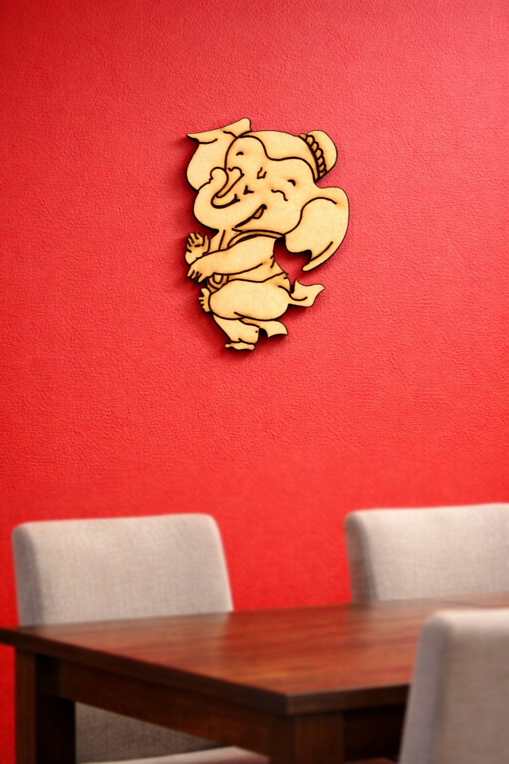 MDF DIY wall decor of a ganesh on a red wall above a wooden table with chairs.
