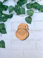 DIY MDF Santa face cutout for Christmas craft mounted on a white textured brick wall