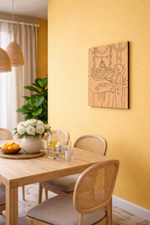 Dining room with wooden table, chairs, and a decorative MDF DIY wall art piece on a yellow wall.