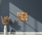 MDF DIY  wall art piece on a dark blue wall with a vase of dried plants below.