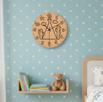 MDF DIY Wooden wall clock with cactus design on a blue wall with white polka dots, books, and a teddy bear in the background.