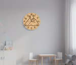 MDF DIY  wall clock with mountain design on a gray wall in a room with children's furniture.
