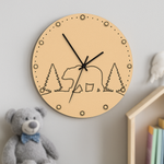 MDF DIY wall clock with bear and tree design on a light gray wall, next to a teddy bear and books.
