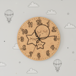 MDF DIY wall clock with star and moon design on a light gray background with cloud and hot air balloon patterns.