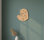 MDF DIY wall art of a stylized face on a green wall with a feather decoration.