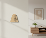 MDF DIY  wall art with a face design on a plain wall, next to a room with a wooden cabinet and framed picture.