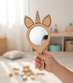 Hand holding a unicorn MDF mirror in a bright playroom.