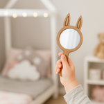 Hand holding a bunny-ear shaped MDF mirror in a kids’ bedroom