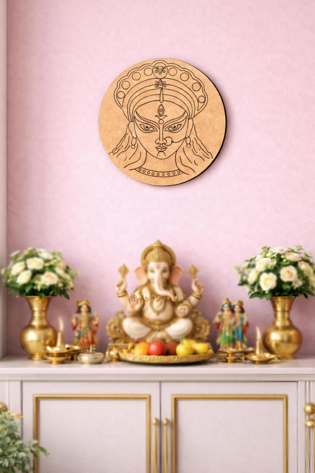 Decorative  DIY MDF Durga  wall art of a face on a pink wall with a small altar featuring a statue and flowers.