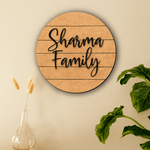 MDF board circular sign with 'Sharma Family' text on a beige wall with decorative elements.