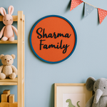 Round sign MDF board with 'Sharma Family' on a wall with toys and decorations